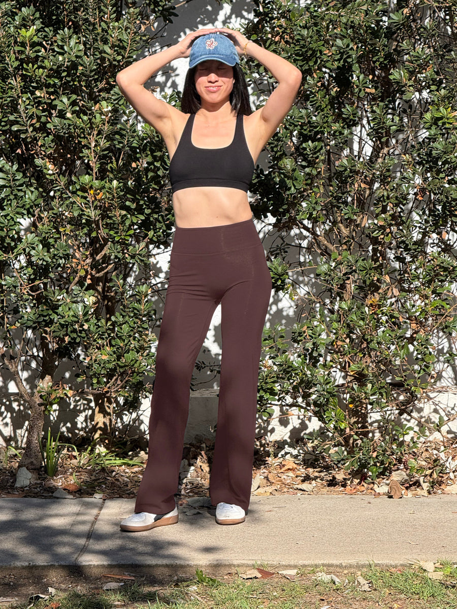 Woman outdoors in Australian bushland wearing a merino sports bra and wide-leg merino pants