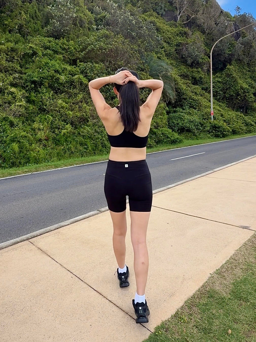 Runner on a road in a merino sports bra and merino shorts, seen from behind