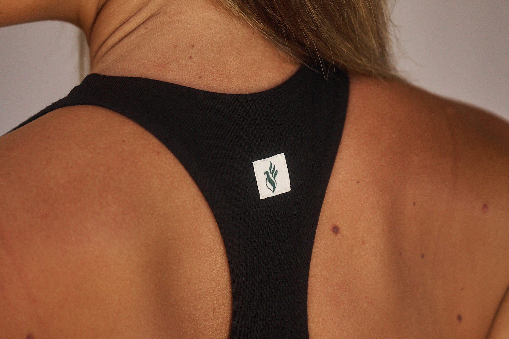 backshot-close-up-of-model-indoors-wearing-estroni-merino-caviar-black-racerback-sports-bra