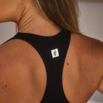 backshot-close-up-of-model-indoors-wearing-estroni-merino-caviar-black-racerback-sports-bra